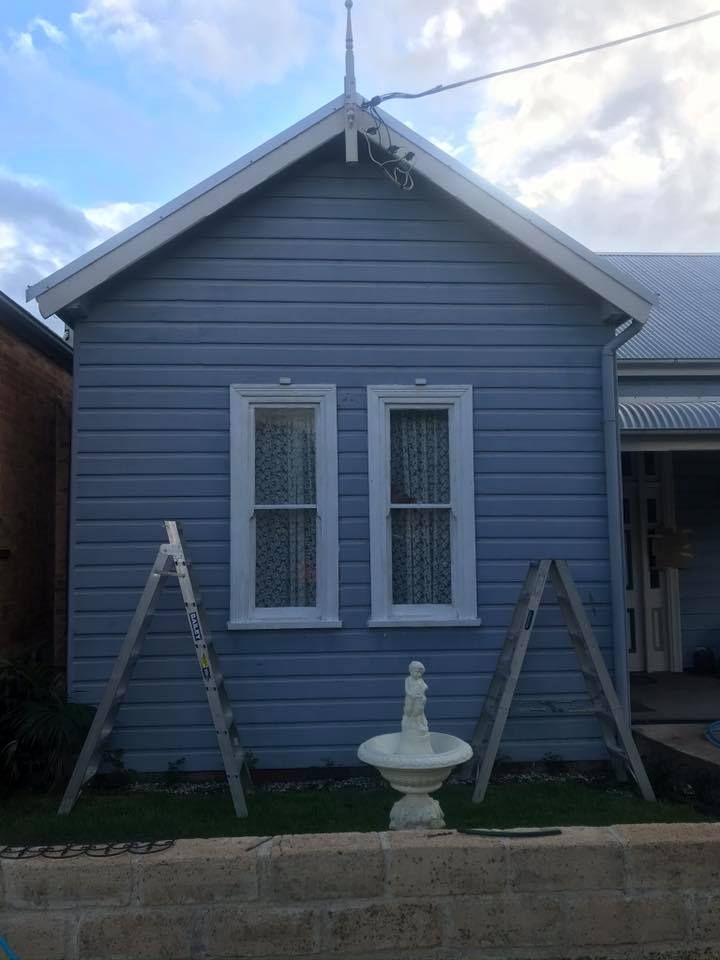 A small blue house with a fountain in front of it