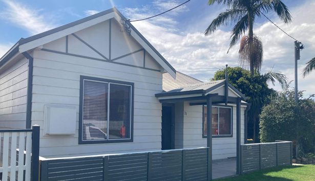 A small white house with a palm tree in the background — Heritage Window Awnings in the Hunter Valley, NSW
