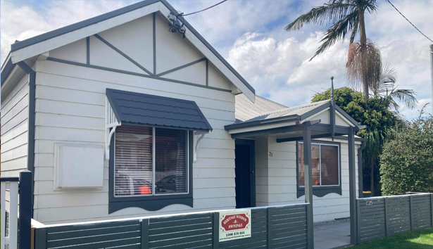 A small white house with a fence around it — Heritage Window Awnings in the Hunter Valley, NSW