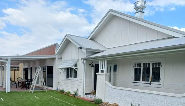 A white house with a white roof is sitting on top of a lush green lawn — Heritage Window Awnings in the Hunter Valley, NSW