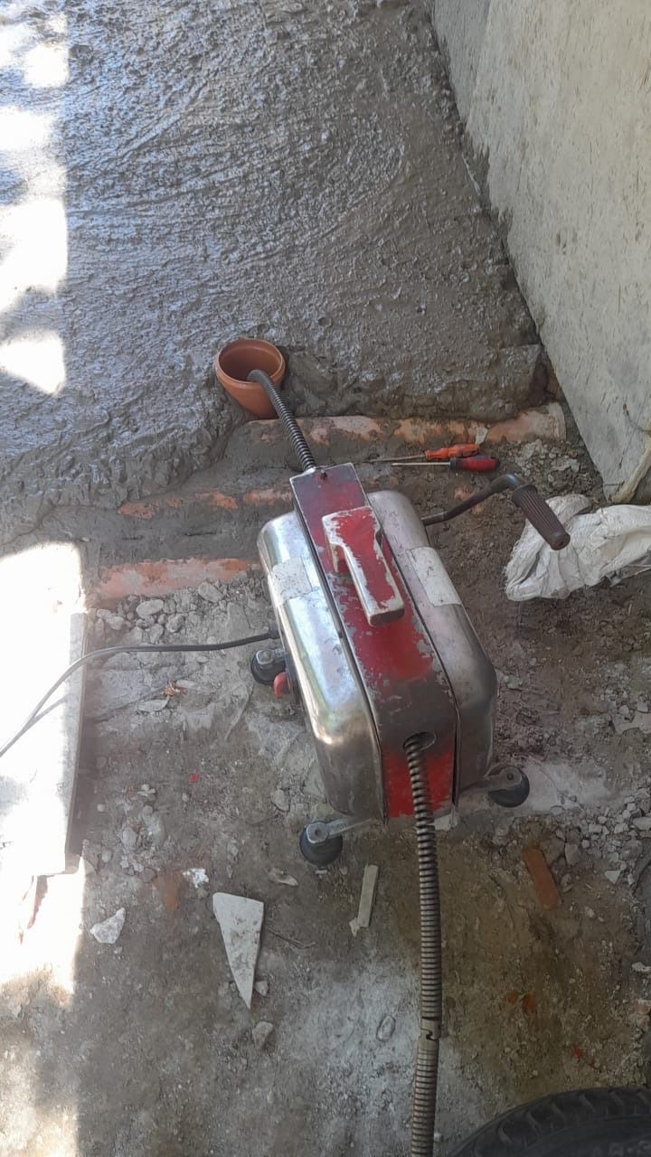 Una máquina portátil de color rojo y plateado se encuentra sobre un suelo de hormigón mojado