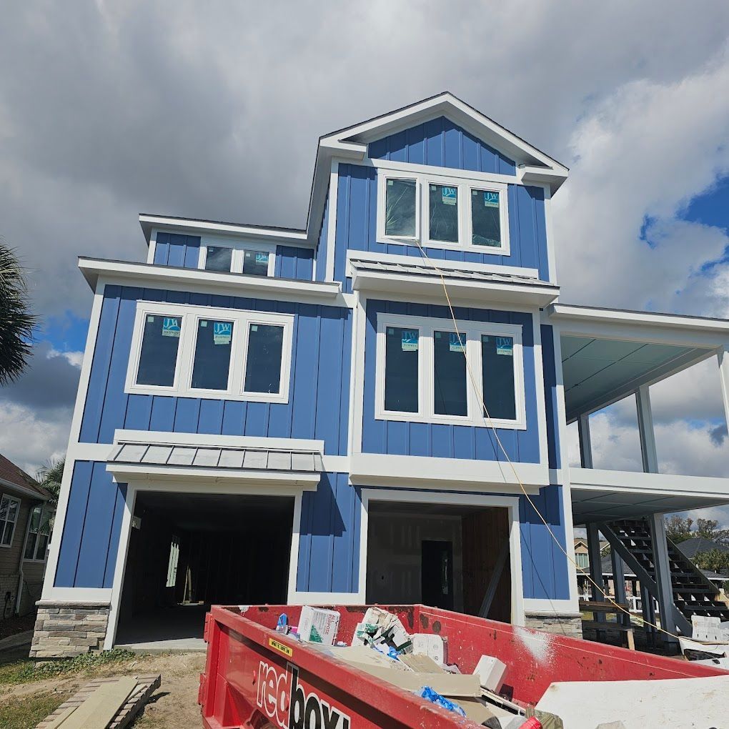 A large blue house with a red dumpster in front of it