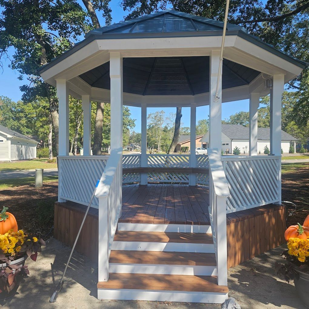 A white gazebo with stairs and pumpkins in front of it