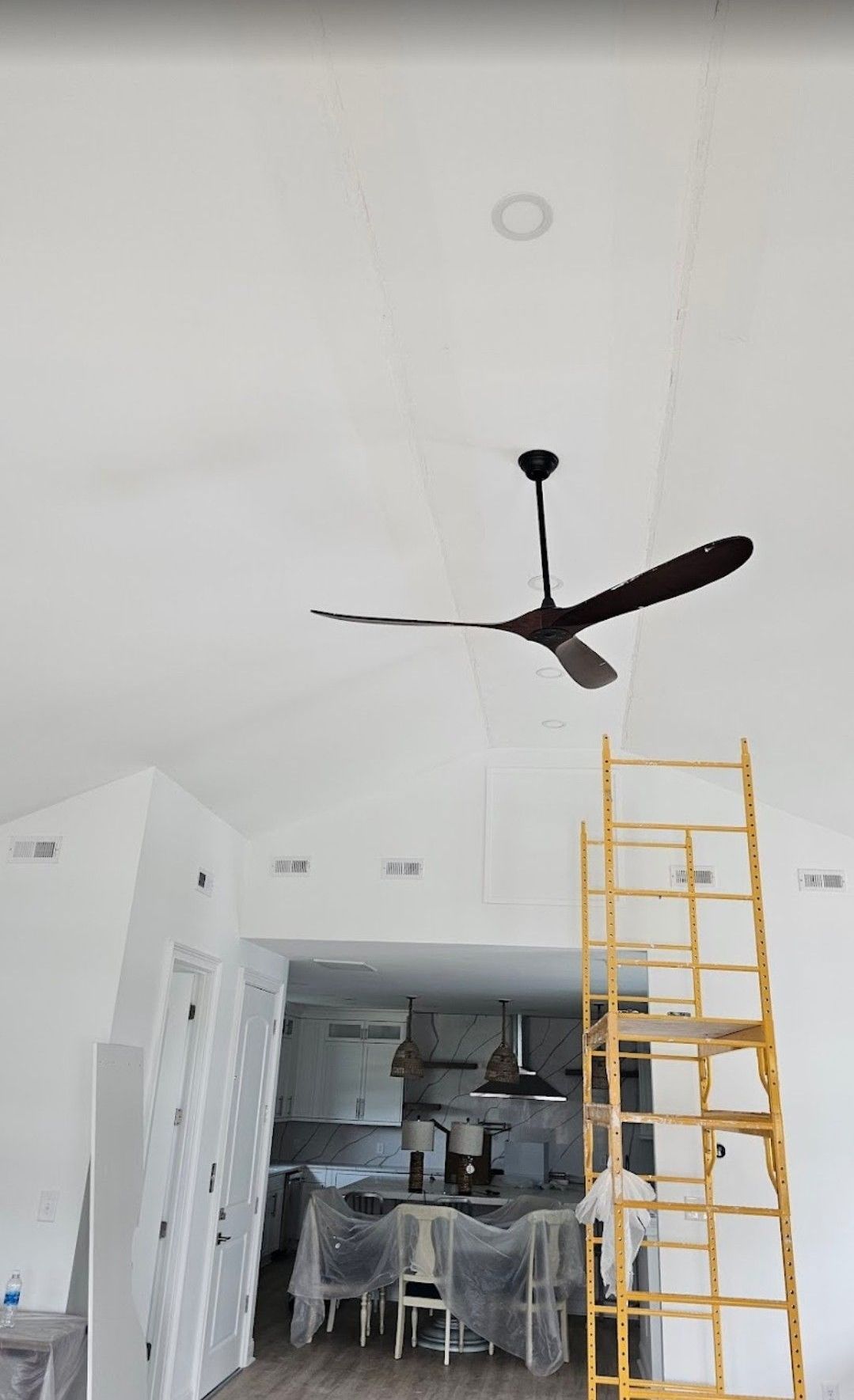 A long wooden walkway leading to a house with a blue building in the background.