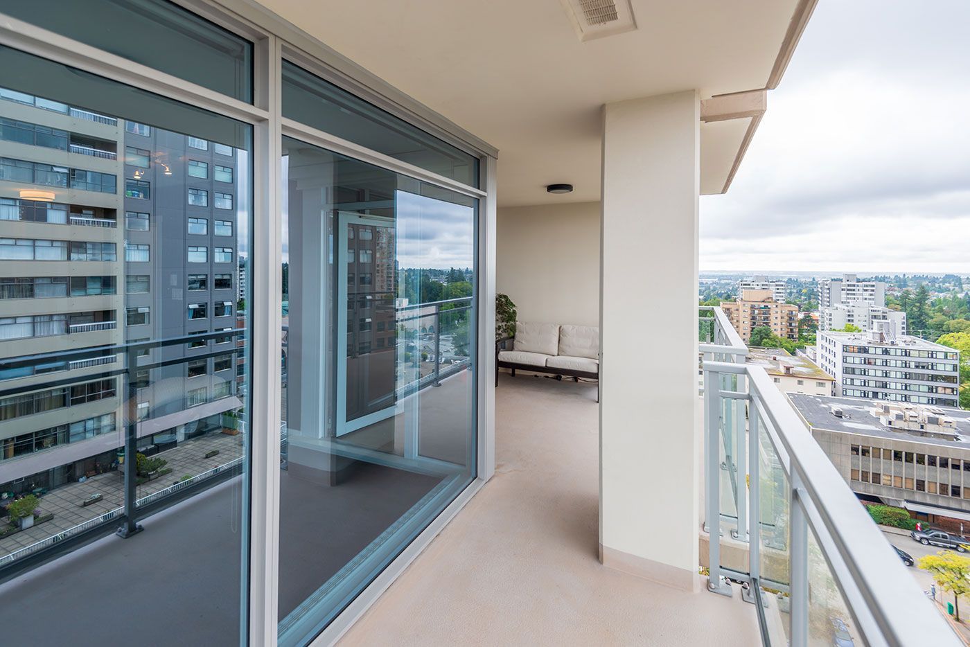 A large balcony with lots of windows and a view of a city.