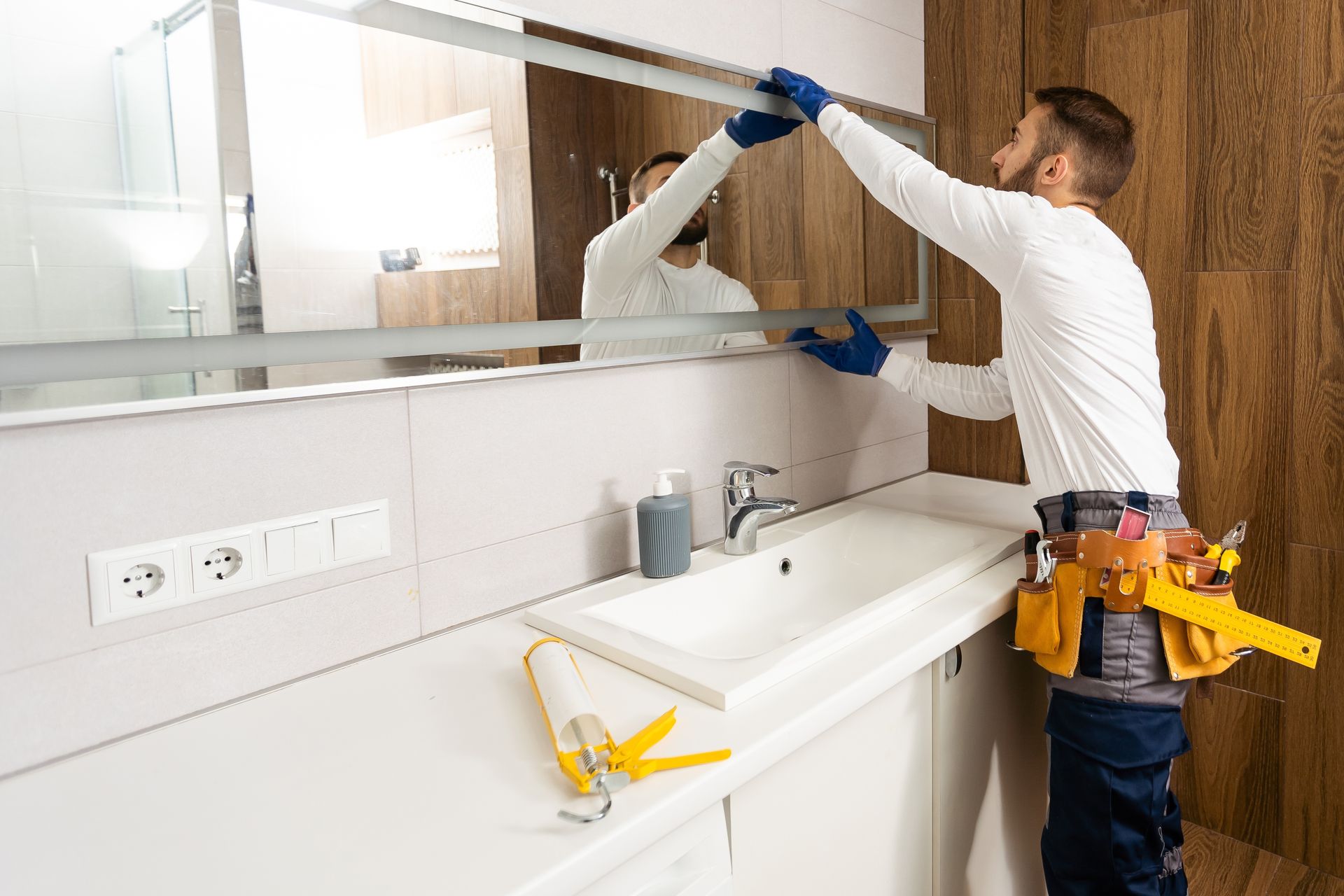 A man is installing a mirror in a bathroom.