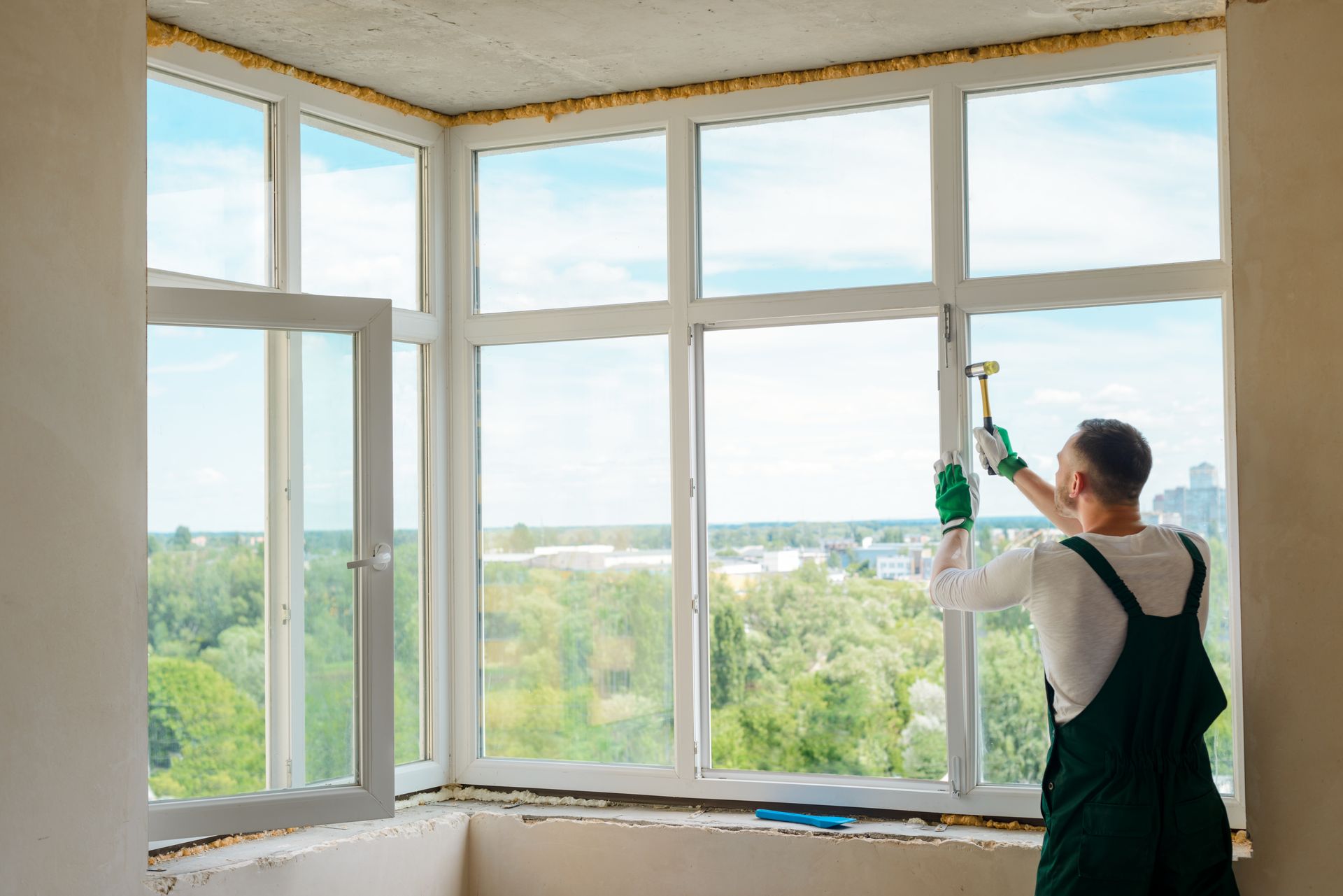 A man is installing a window in a room with a hammer.