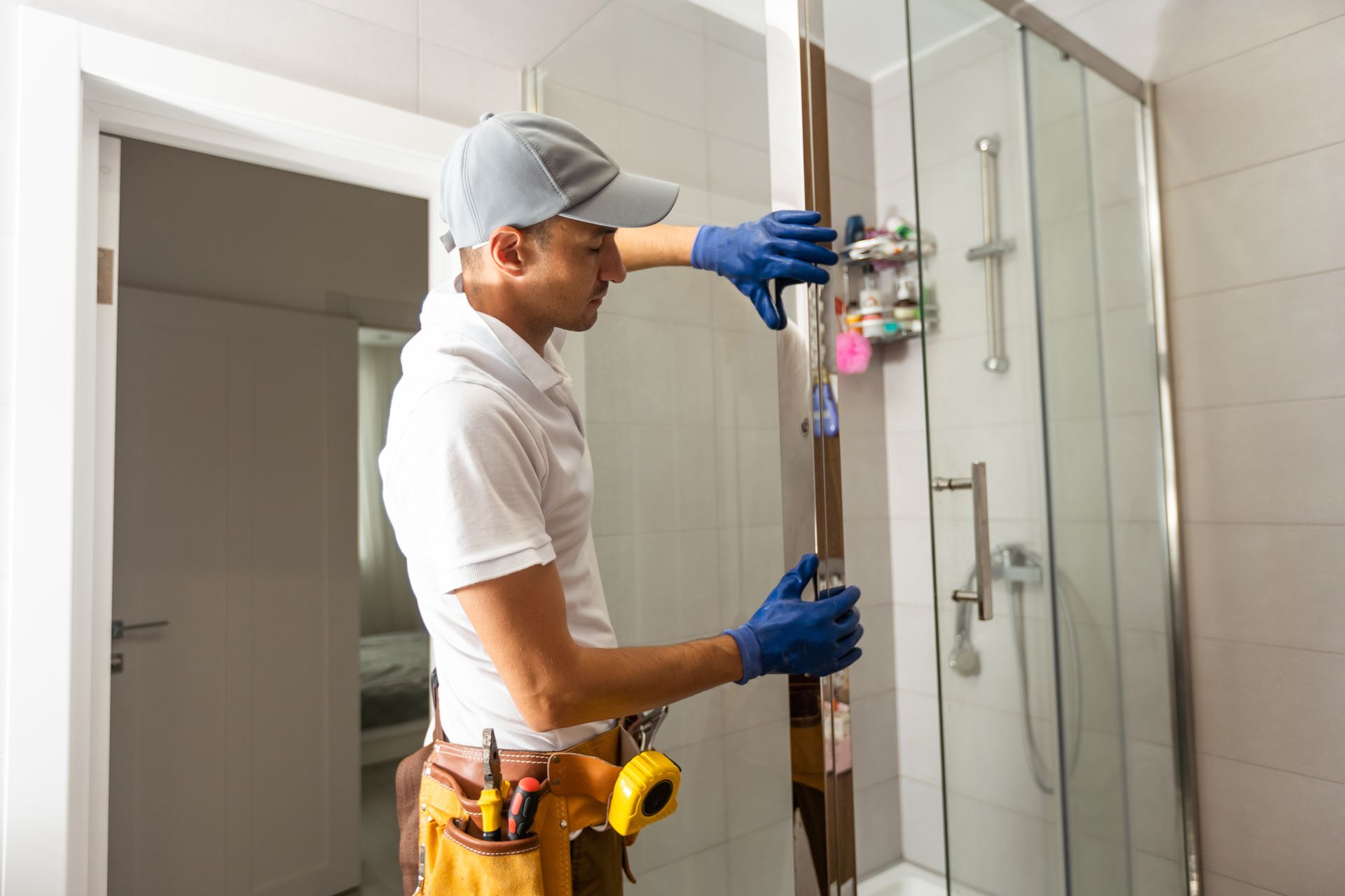 A man is installing a shower door in a bathroom.