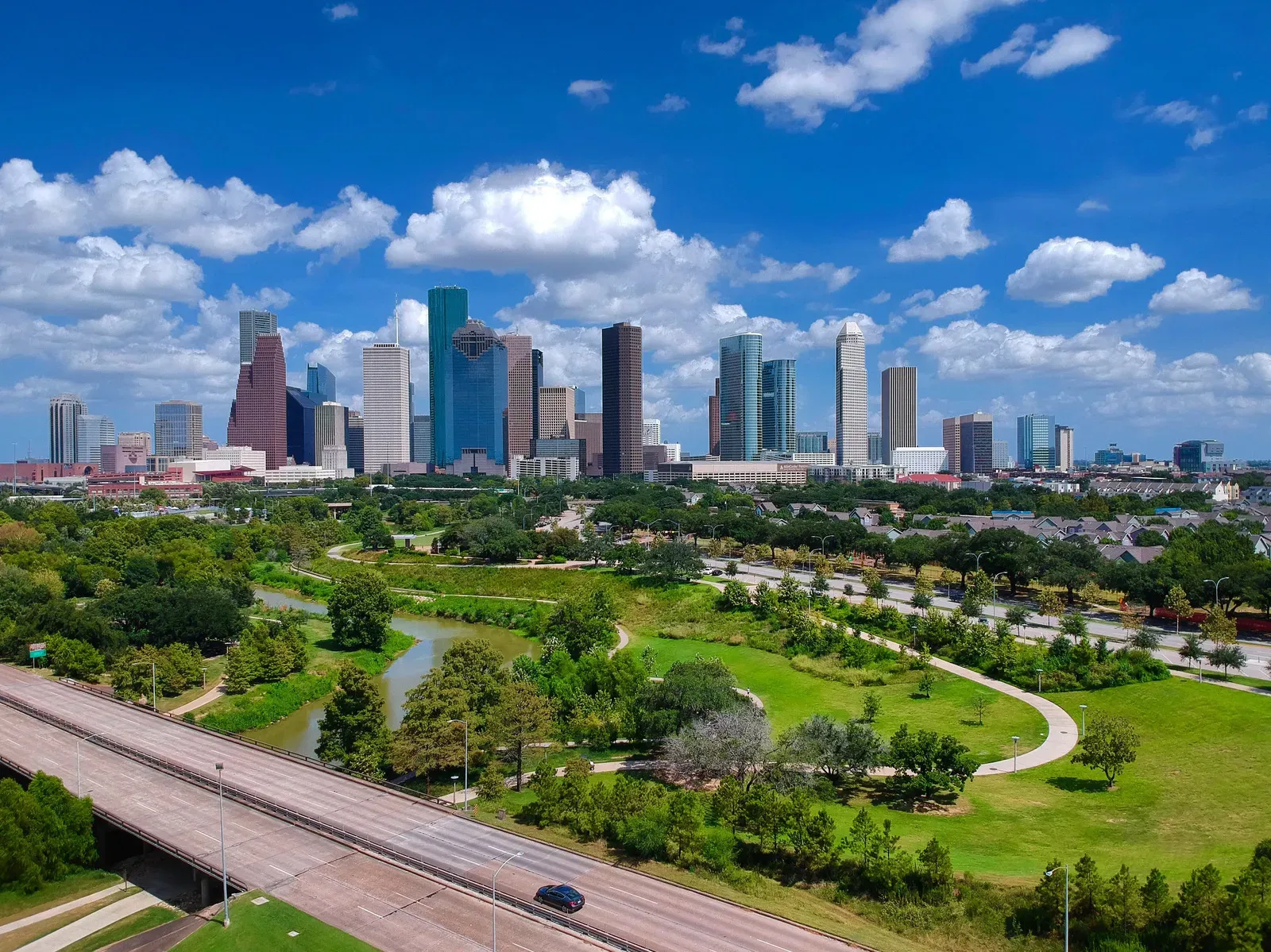 Houston skyline with green park and blue sky.