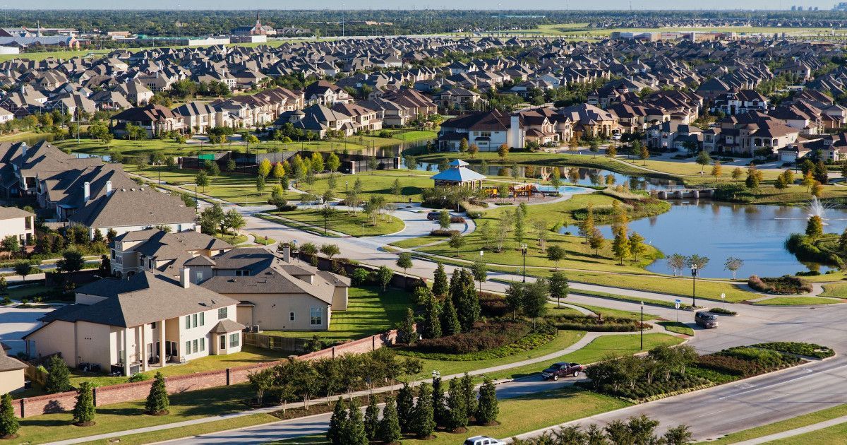 Suburban residential neighborhood with houses, a pond, and green spaces.