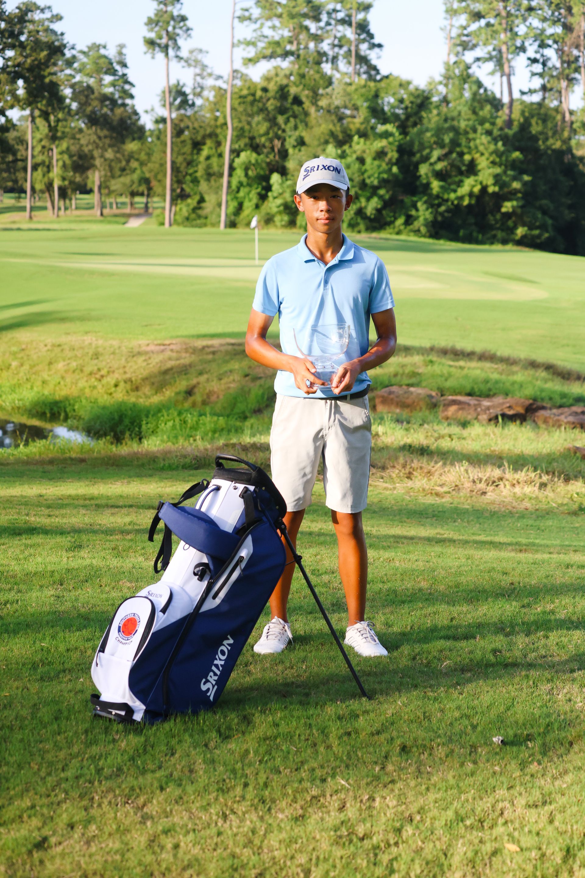 A man is standing next to a golf bag on a golf course.