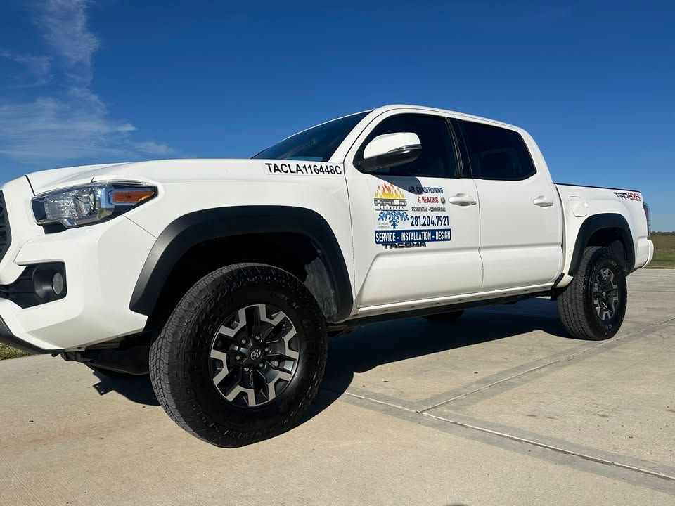 White Toyota Tacoma truck with black wheels and logo, parked on a concrete surface. Clear blue sky.