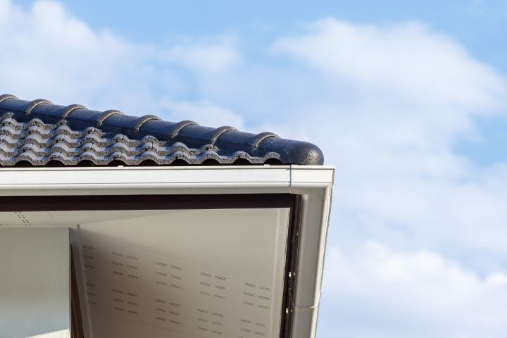 Open window under a blue tiled roof against a cloudy sky
