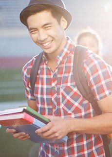 Juniors & Young Men — Smiling Student with Books on Hand in Vista, CA