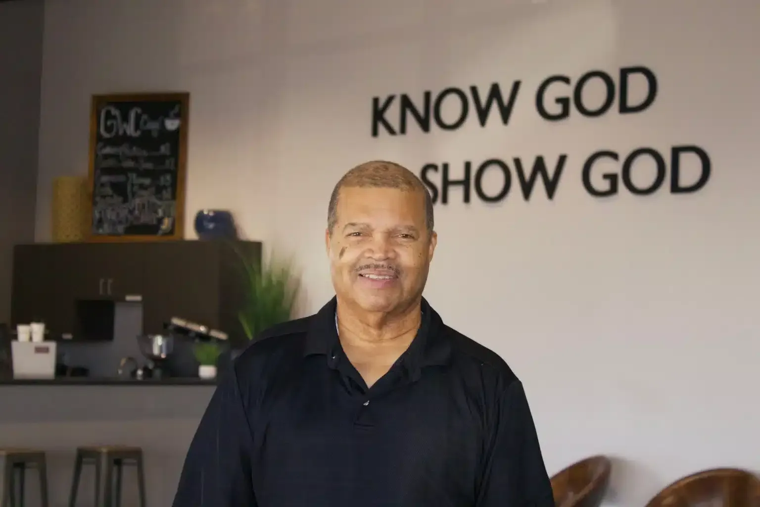 Man smiling in front of a wall with text 