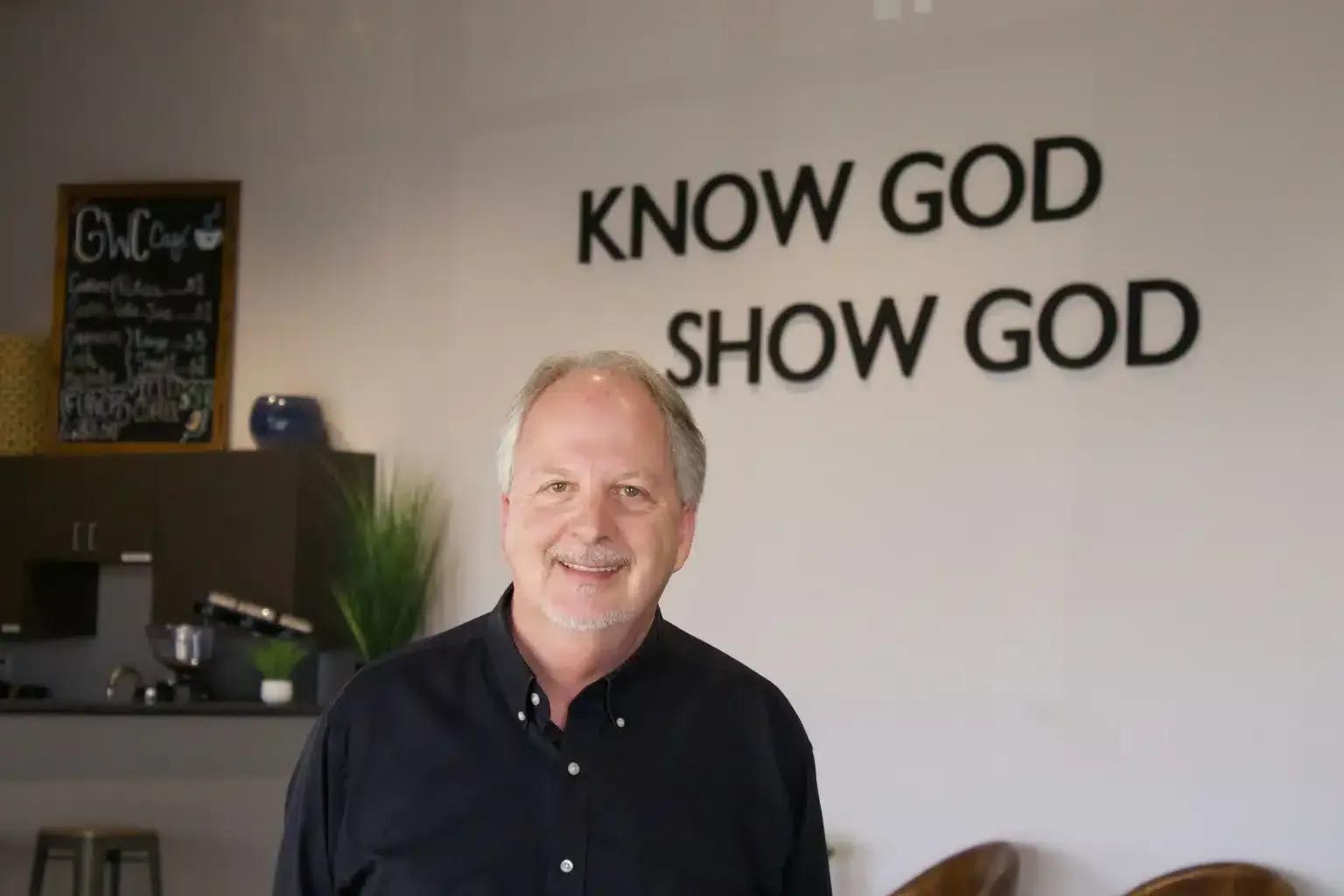 Man smiling in front of a wall with 