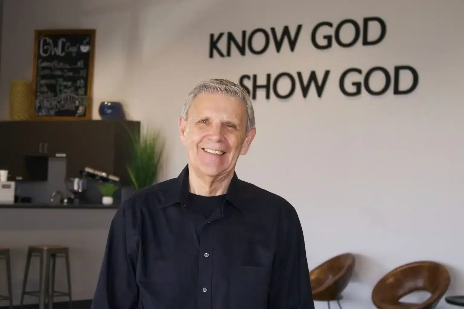 Man smiling in front of a wall with 