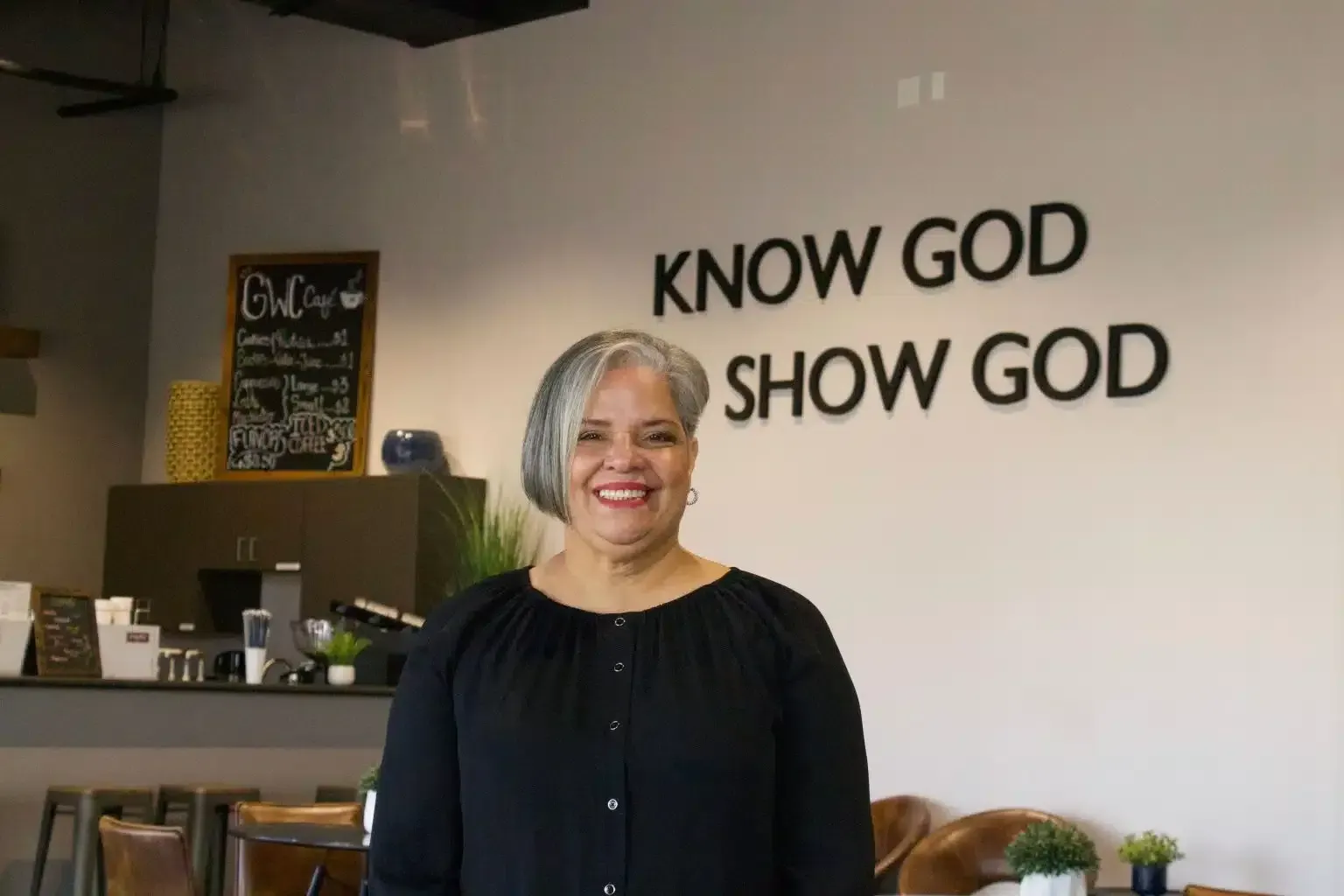 Woman smiling in front of a wall with text 