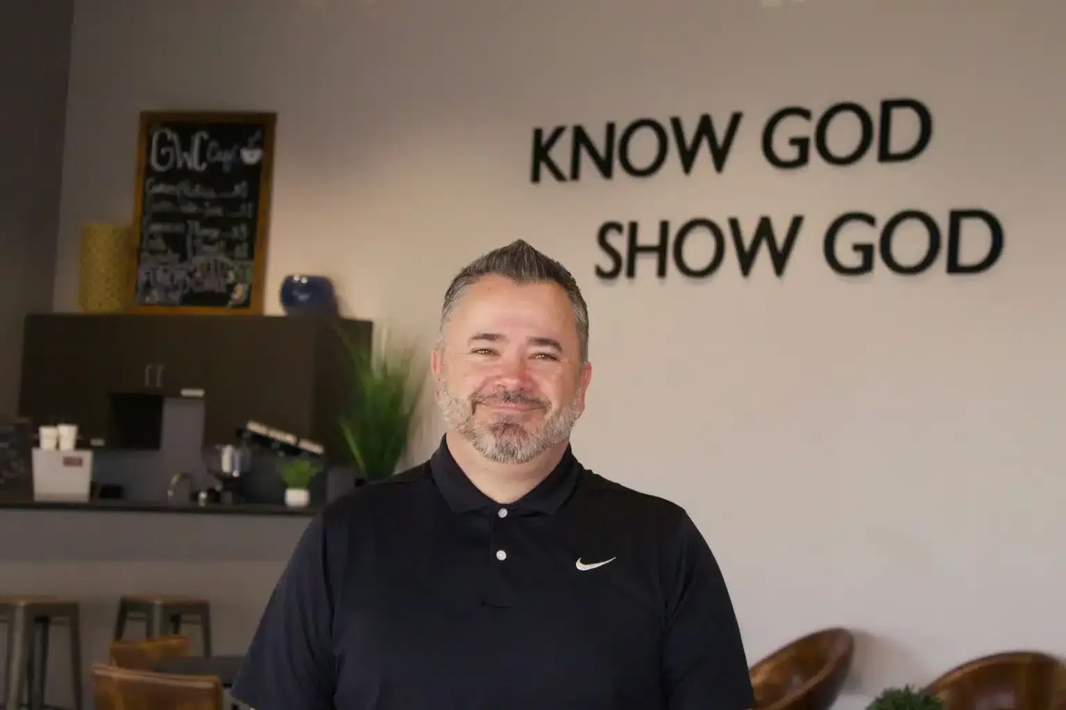Man in black shirt smiles in front of 