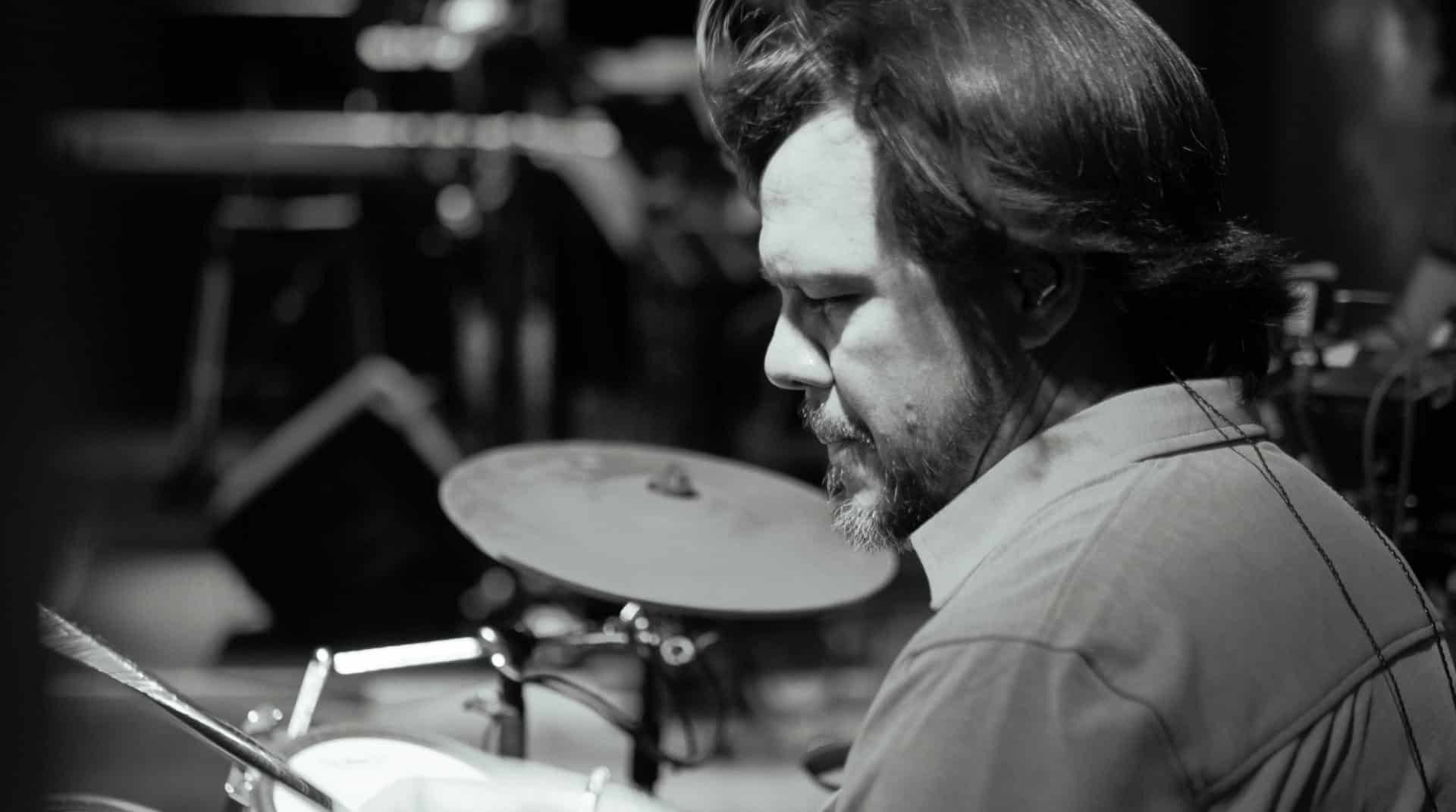 Drummer playing drums in black and white.