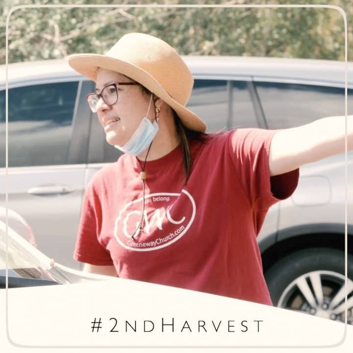 Woman in hat and red shirt directing outside. 