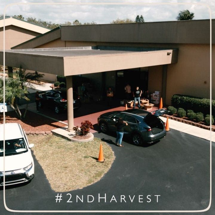 Cars loading donations outside a building with the hashtag #2NDHARVEST.