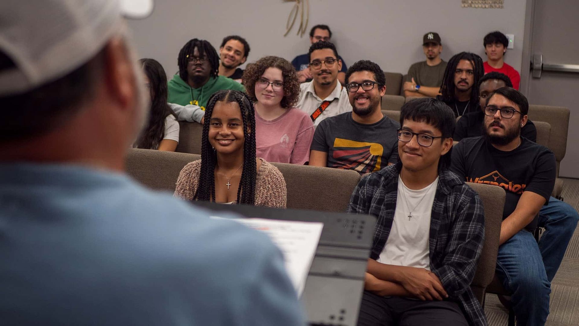 A group of people listens to a person speaking at a lecture or presentation.