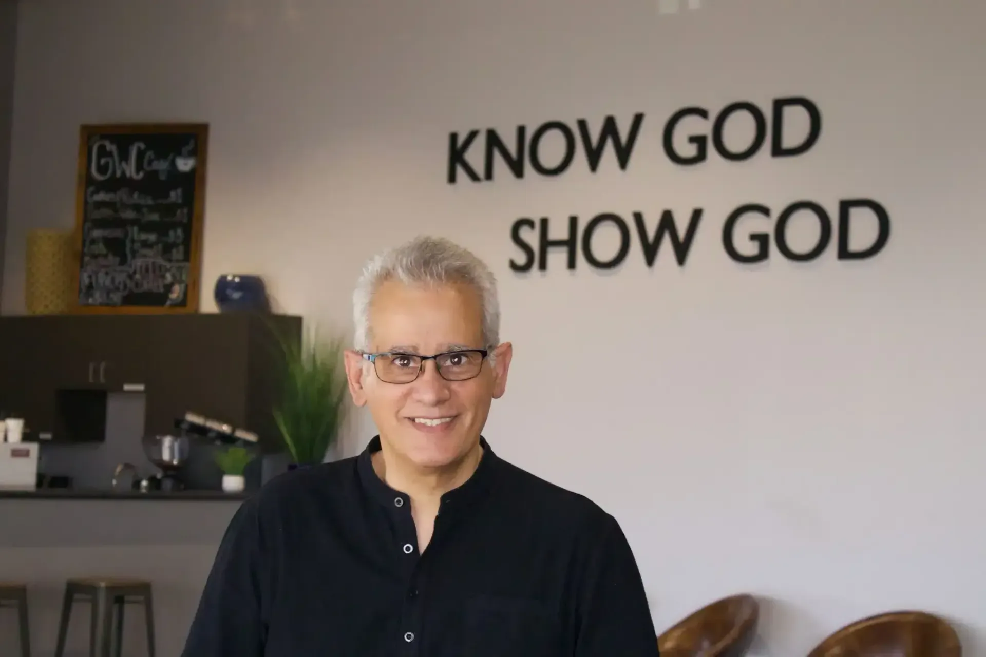 Man smiling in front of a wall with 