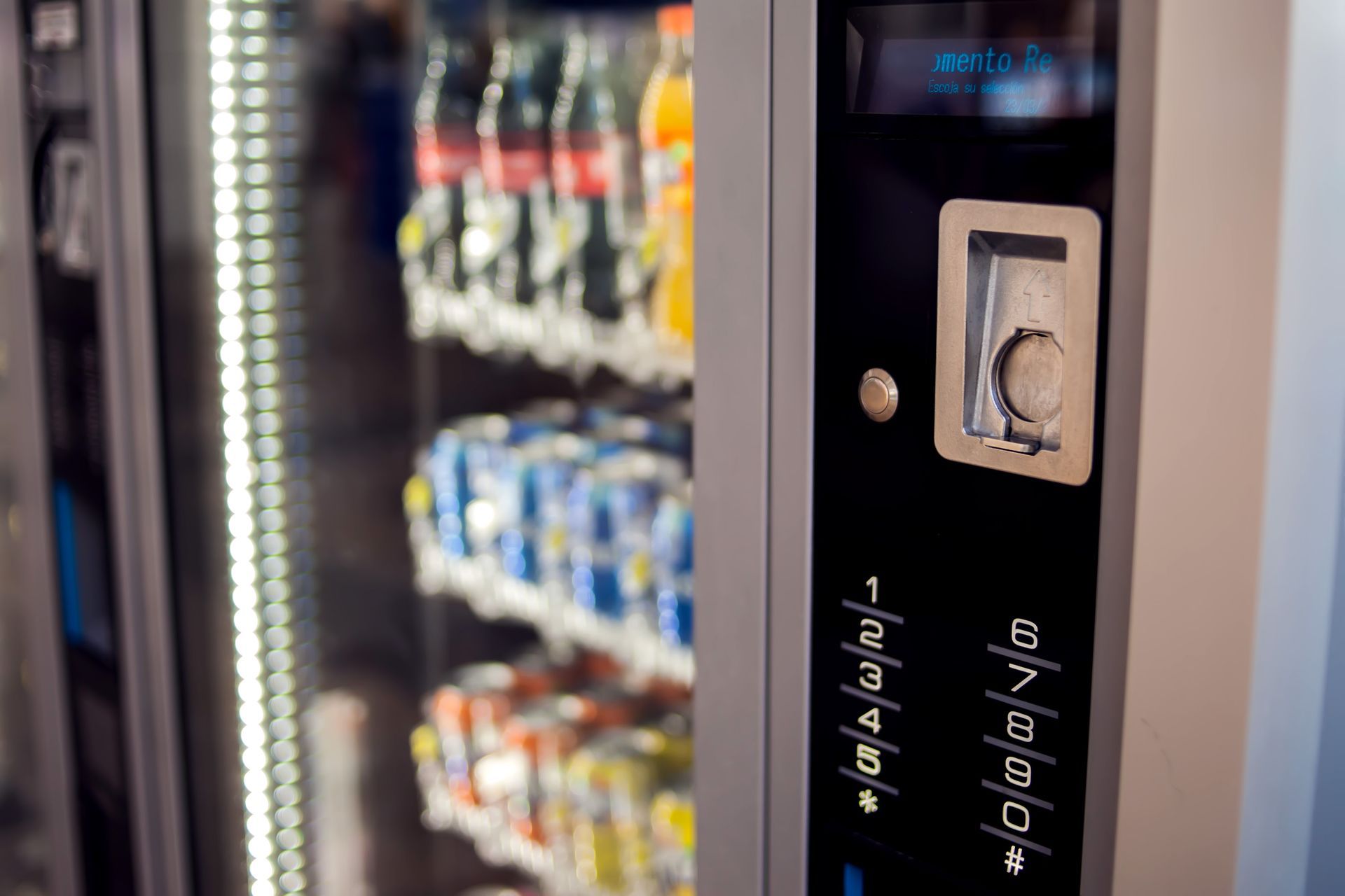 Close-up of a vending machine control panel with a keypad and card reader, next to product displays.