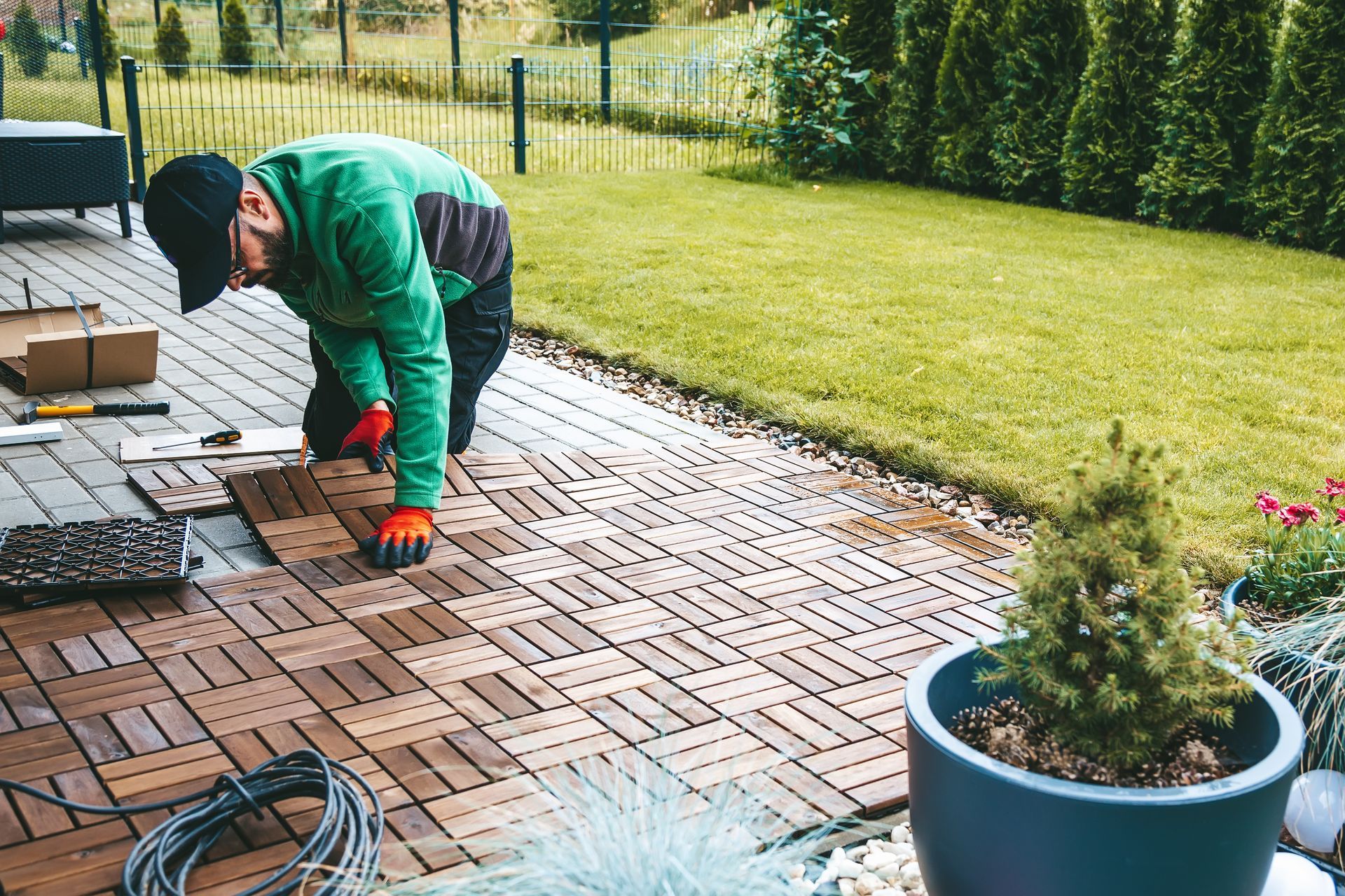 A man is laying wooden tiles on a patio.