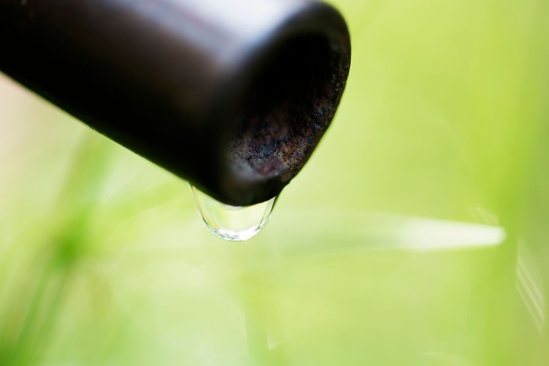 A close up of a drop of water coming out of a pipe.