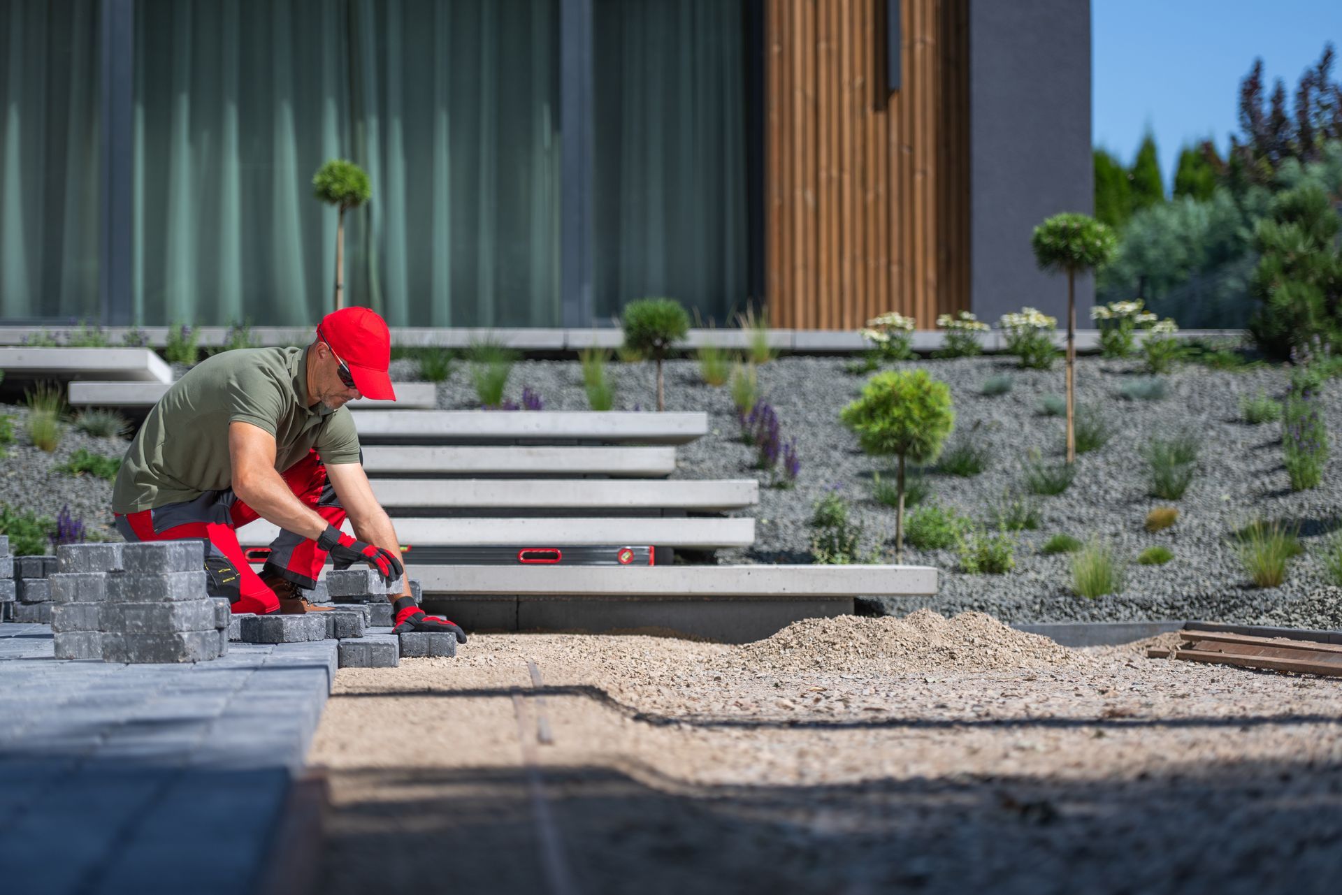 A man is laying bricks on the ground in front of a house.