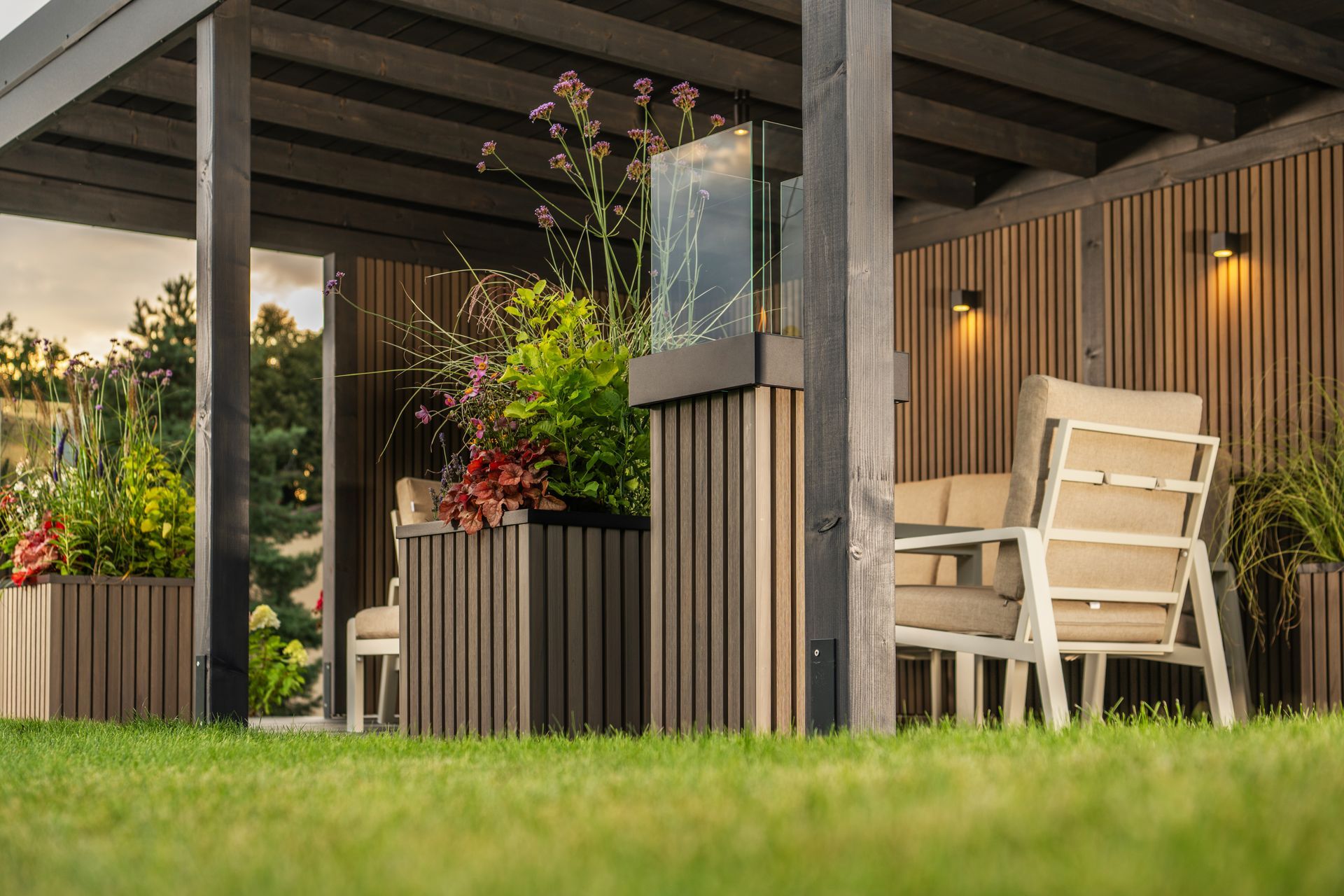 Outdoor seating area with a wooden pergola, tan furniture, and greenery.