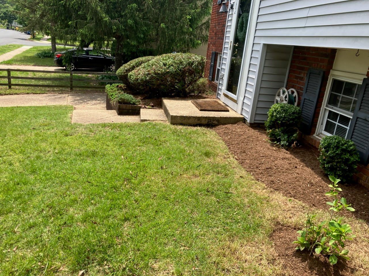 A house with a lush green lawn and a fence in front of it.