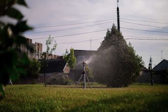A sprinkler is spraying water on a lush green field.