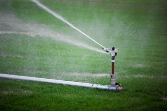 A sprinkler is spraying water on a lush green field.