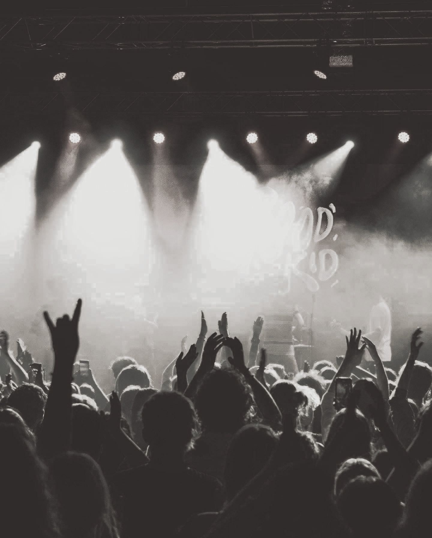 A crowd of people are standing in front of a stage with their hands in the air.