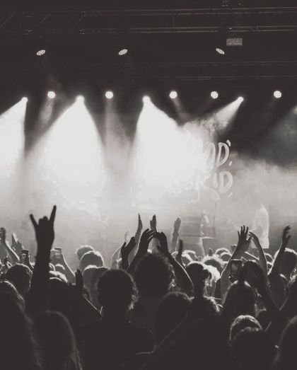 A crowd of people are standing in front of a stage with their hands in the air.