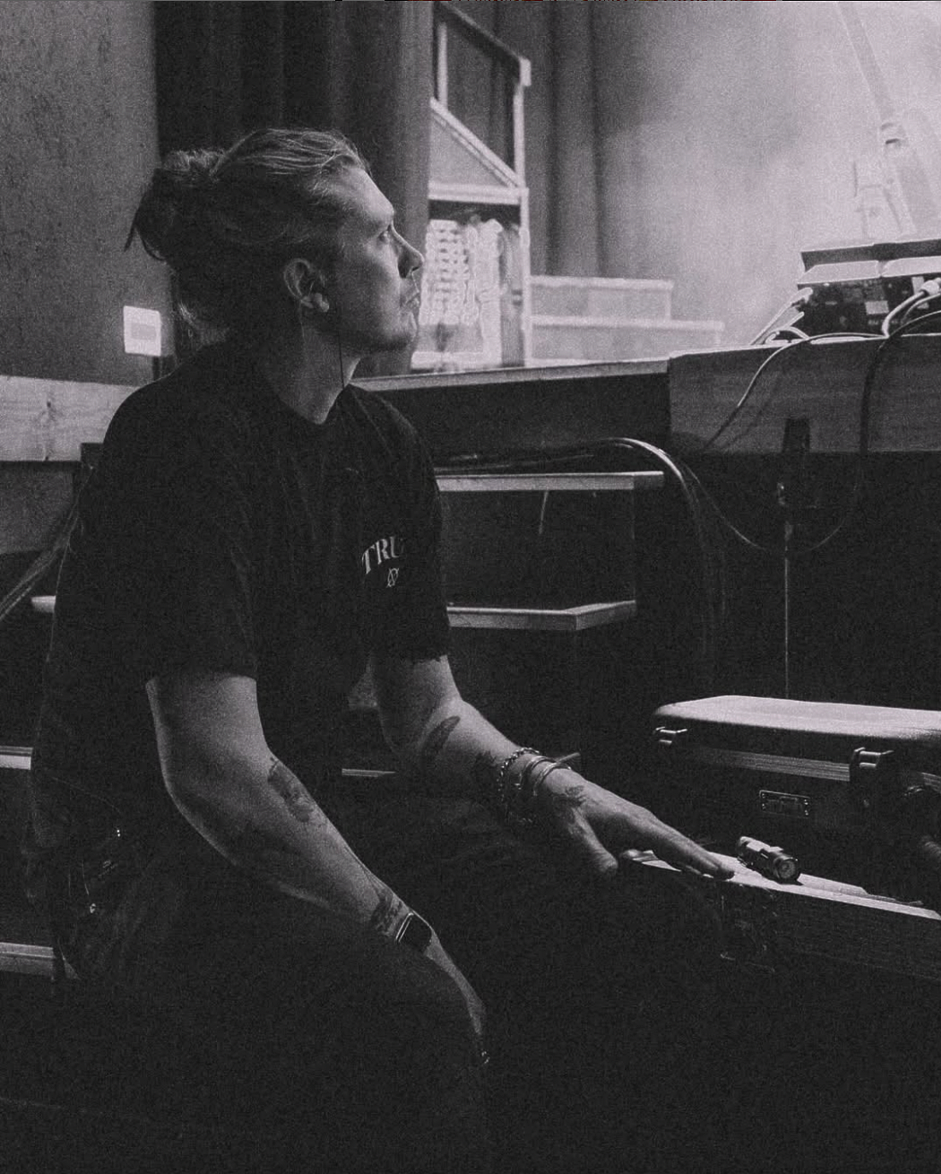 A black and white photo of a man sitting in front of a piano