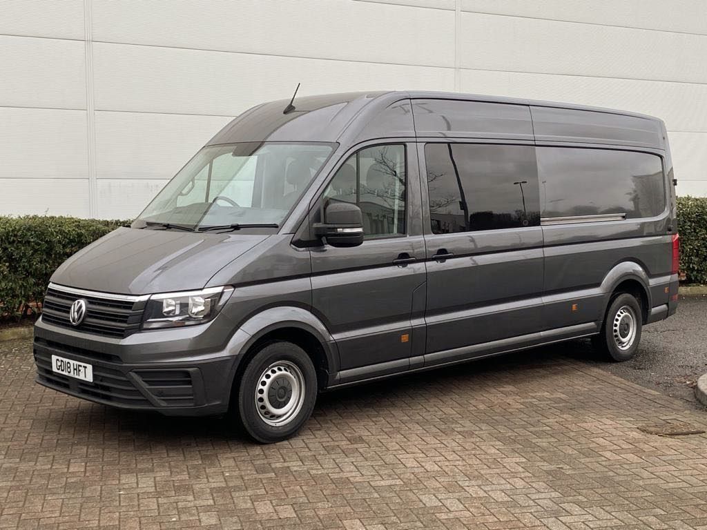 A volkswagen crafter van is parked in a parking lot in front of a building.
