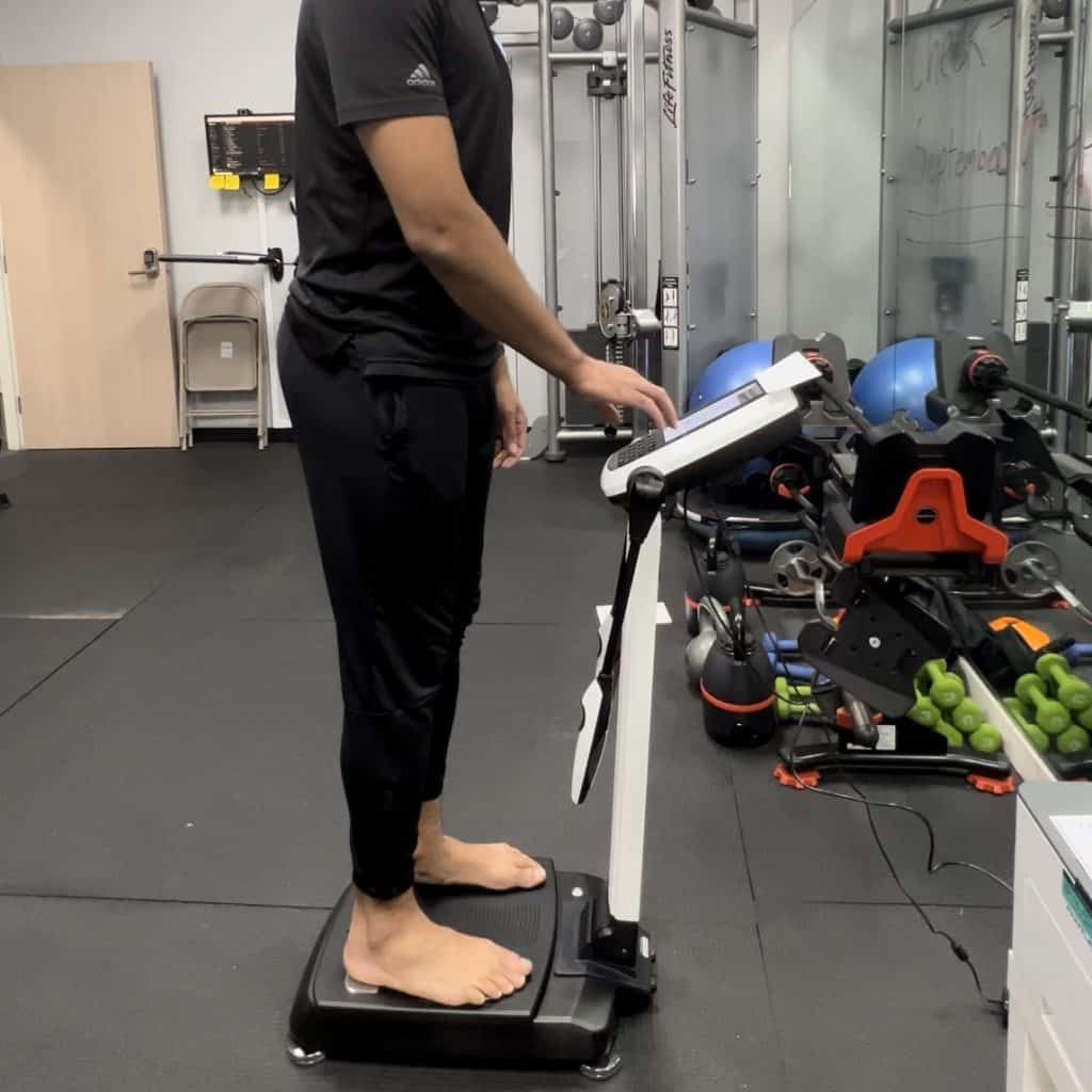 A man is standing on a scale in a gym