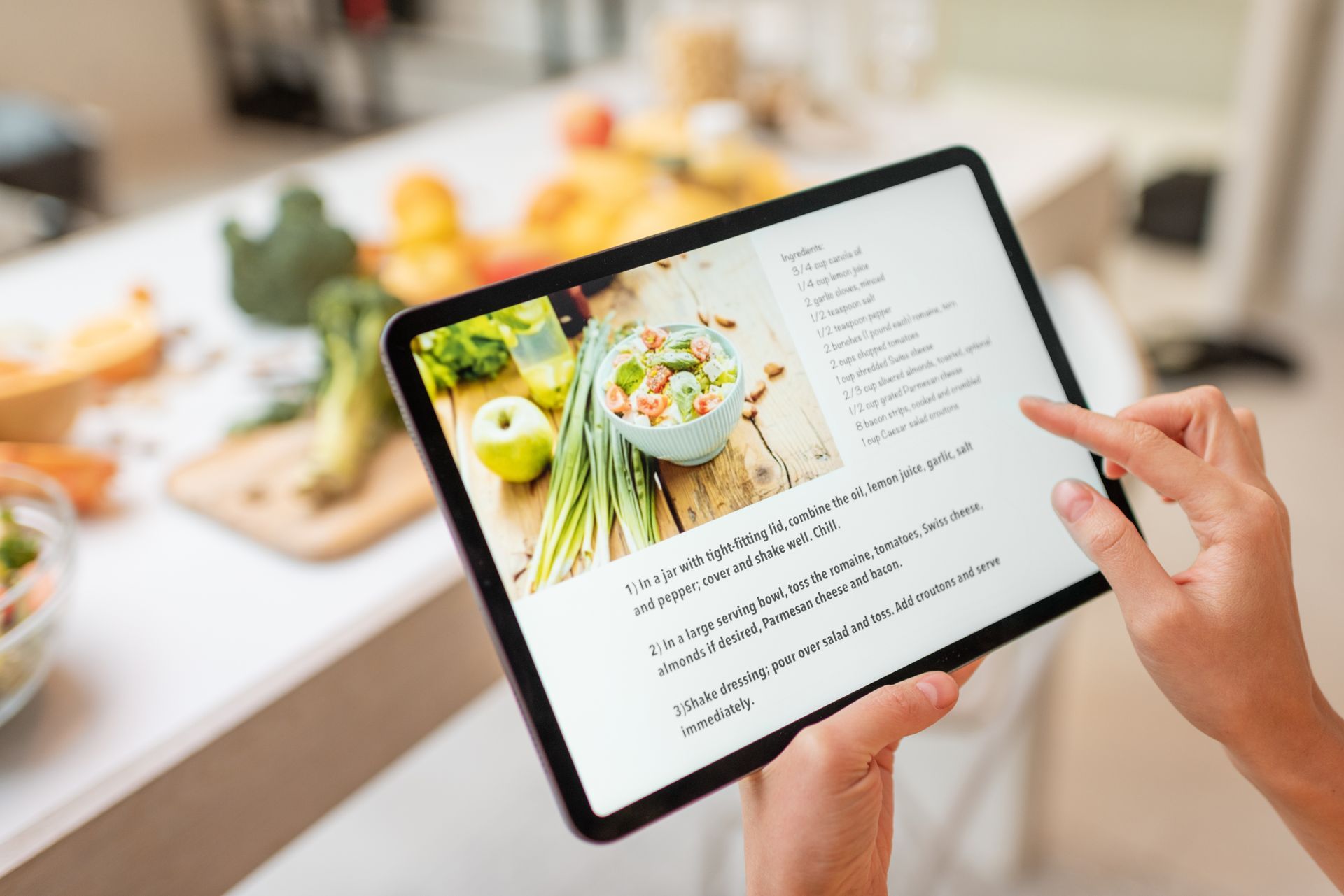 A person is holding a tablet with a recipe on it.