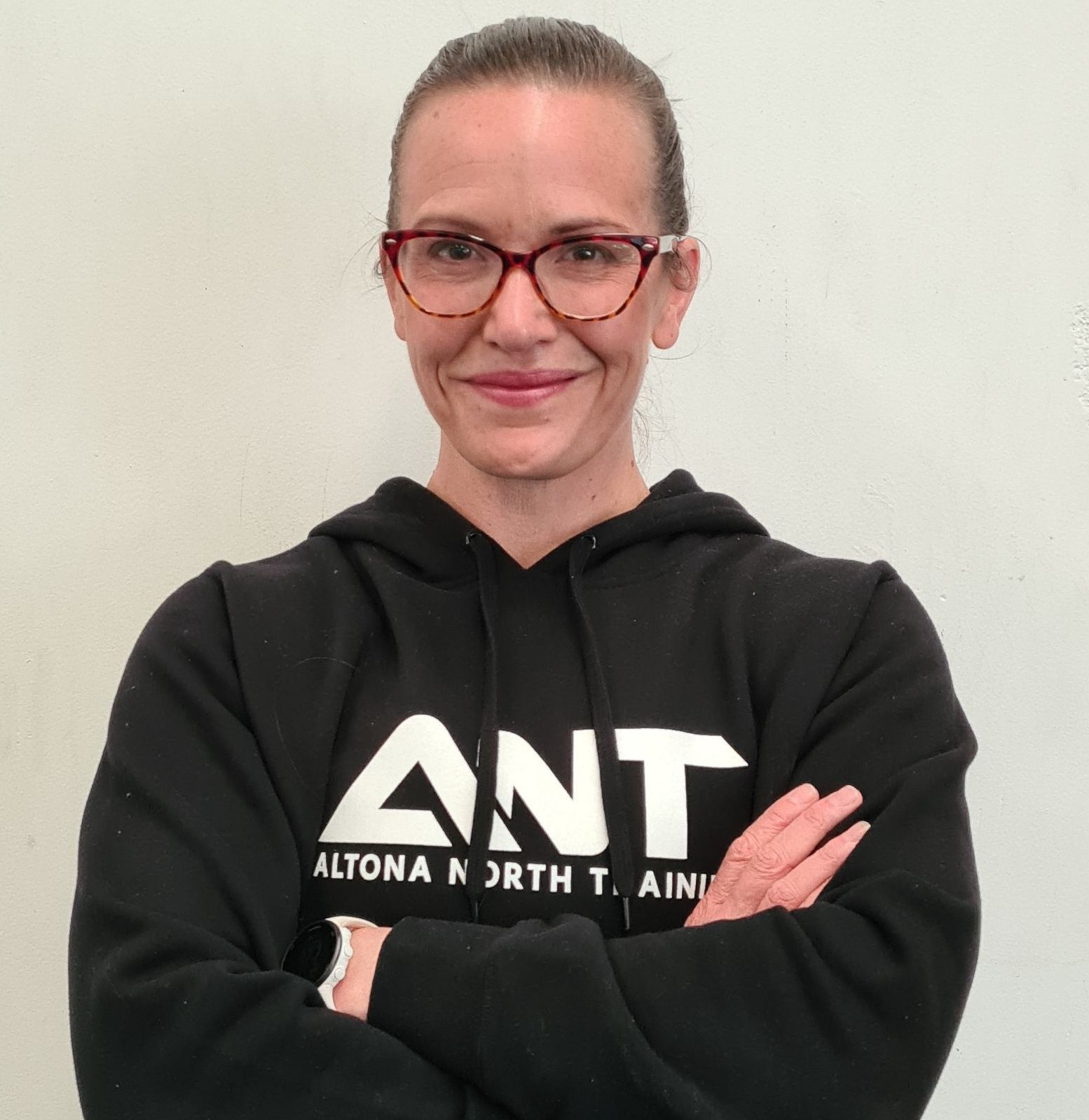 A woman wearing a black ant sweatshirt with her arms crossed