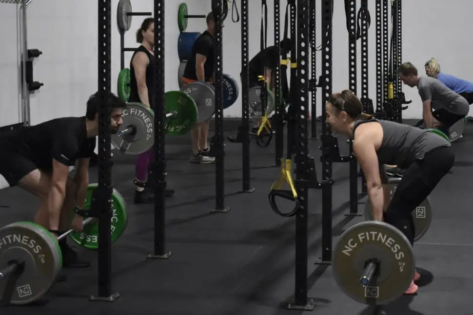 A group of people are lifting weights in a gym.