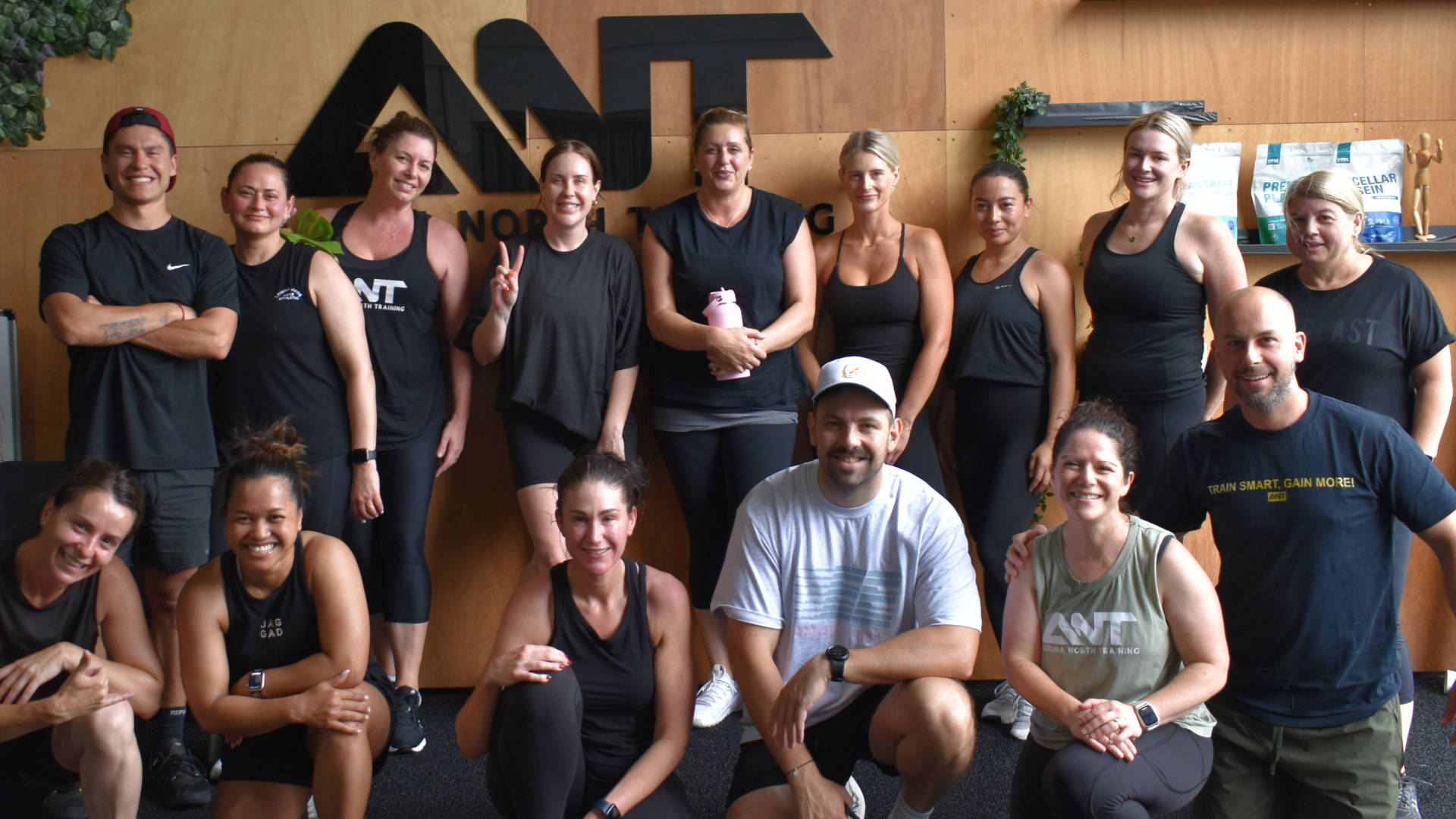 A group of people are posing for a picture in front of a sign that says ant.