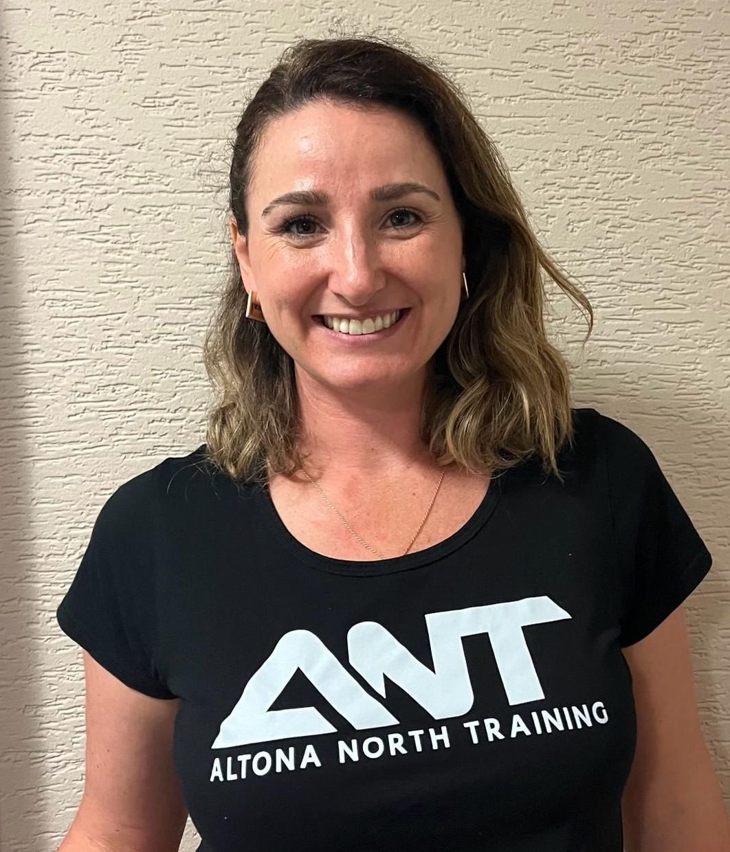 A woman wearing a black ant t-shirt is smiling for the camera.