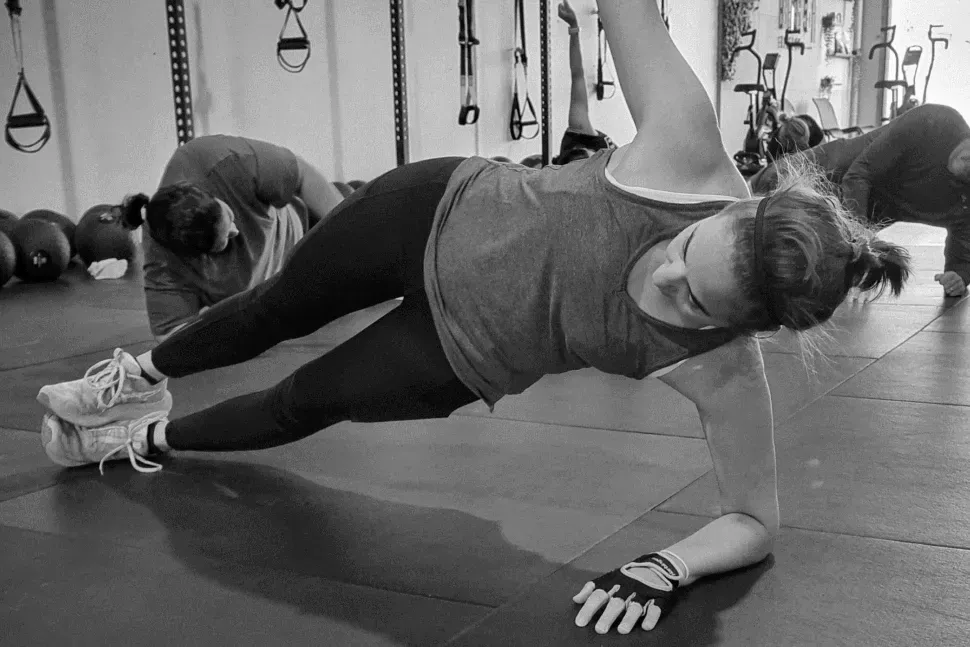 A woman is doing a plank on the floor in a gym.