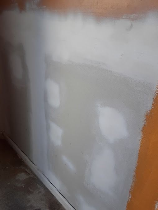 A wall with patches of white drywall compound, ready for painting.