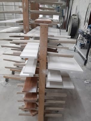 Wooden rack holding painted cabinet doors, drying in a workshop.