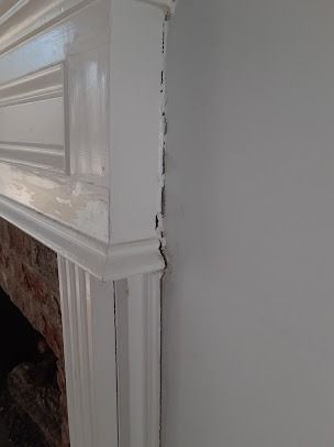 White fireplace mantel and wall corner, partially obscuring a brick fireplace opening.